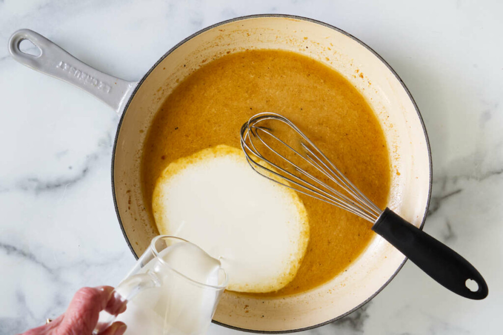 Pouring cream into the skillet tarragon sauce.