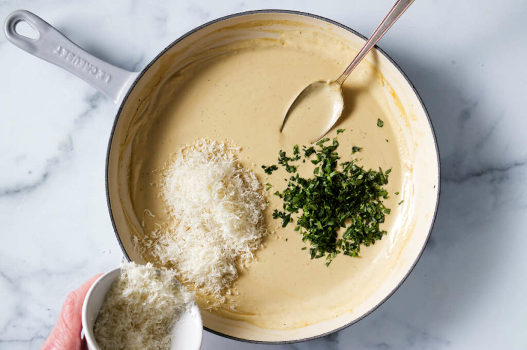 Adding cheese and fresh tarragon in cream sauce.