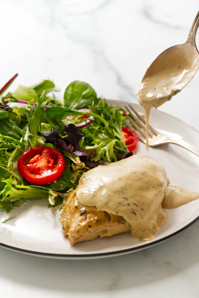 A dinner plate showing chicken with creamy tarragon sauce next to a salad.