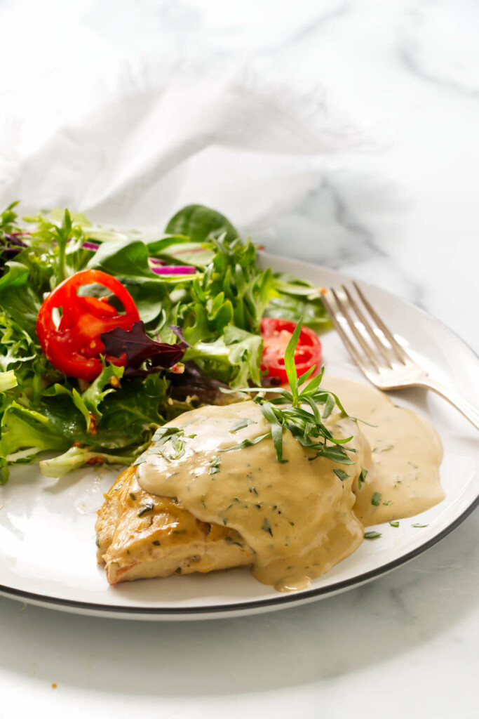 Chicken with tarragon cream sauce on a plate with a salad.