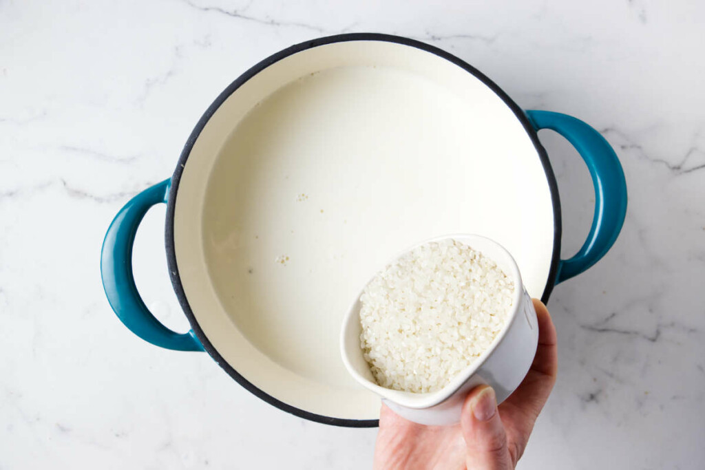 Pouring short grain rice into a pot with milk and cream.