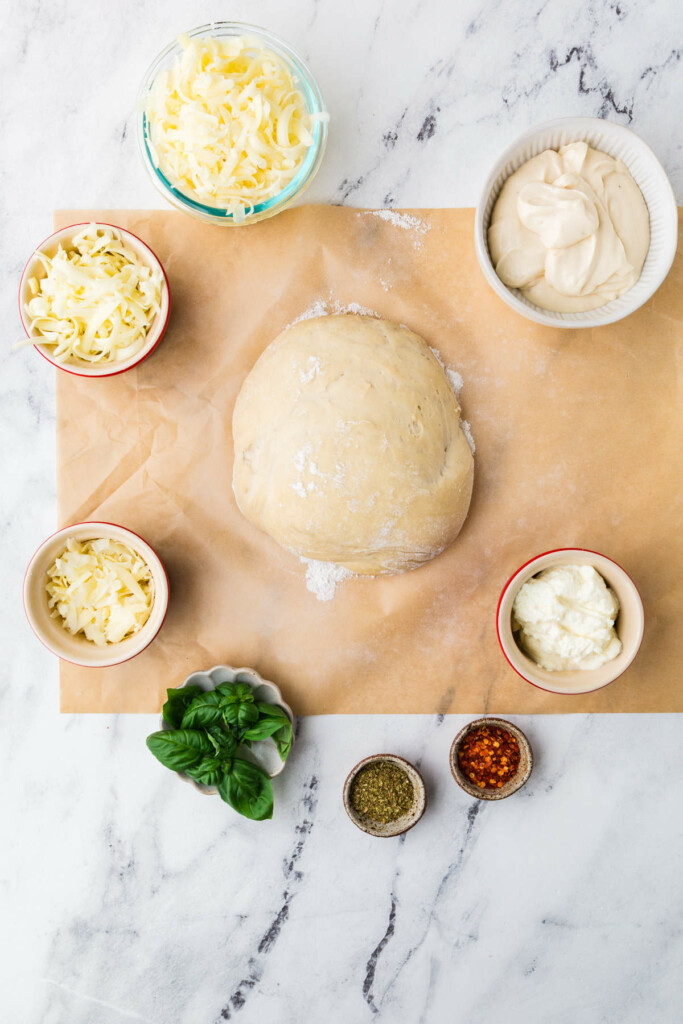 Pizza-making ingredients on a white marble .