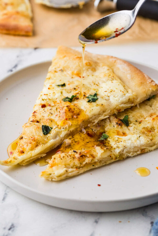 Slices of white pizza with herbs and red pepper flakes.