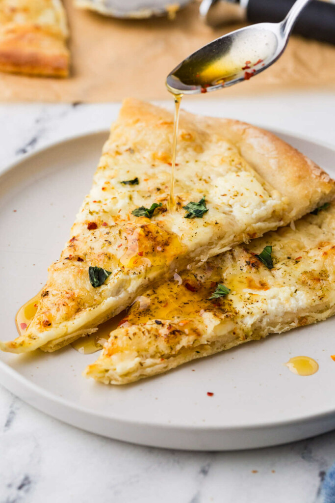 Slices of white pizza with herbs and red pepper flakes.