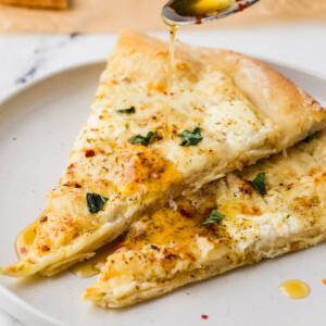 Two thick crust cheese pizza slices with white sauce.