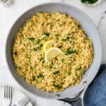 Parmesan lemon orzo in a skillet next to a plate and forks.
