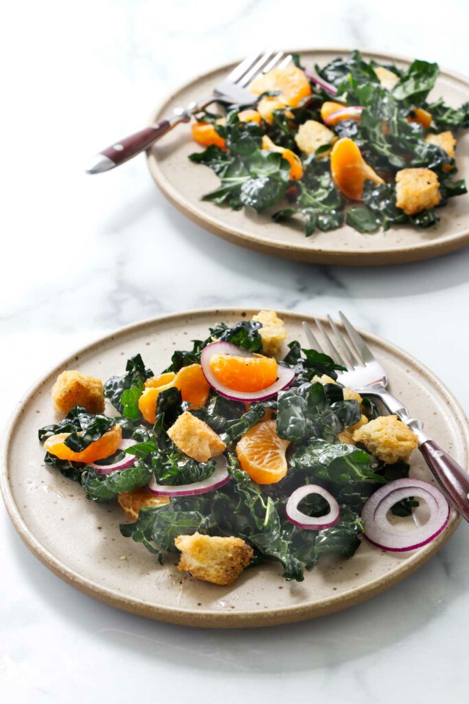 Two plates filled with kale and mandarin salad.