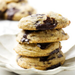 Four soft, chewy chocolate chip cookies with sourdough discard on a white plate.