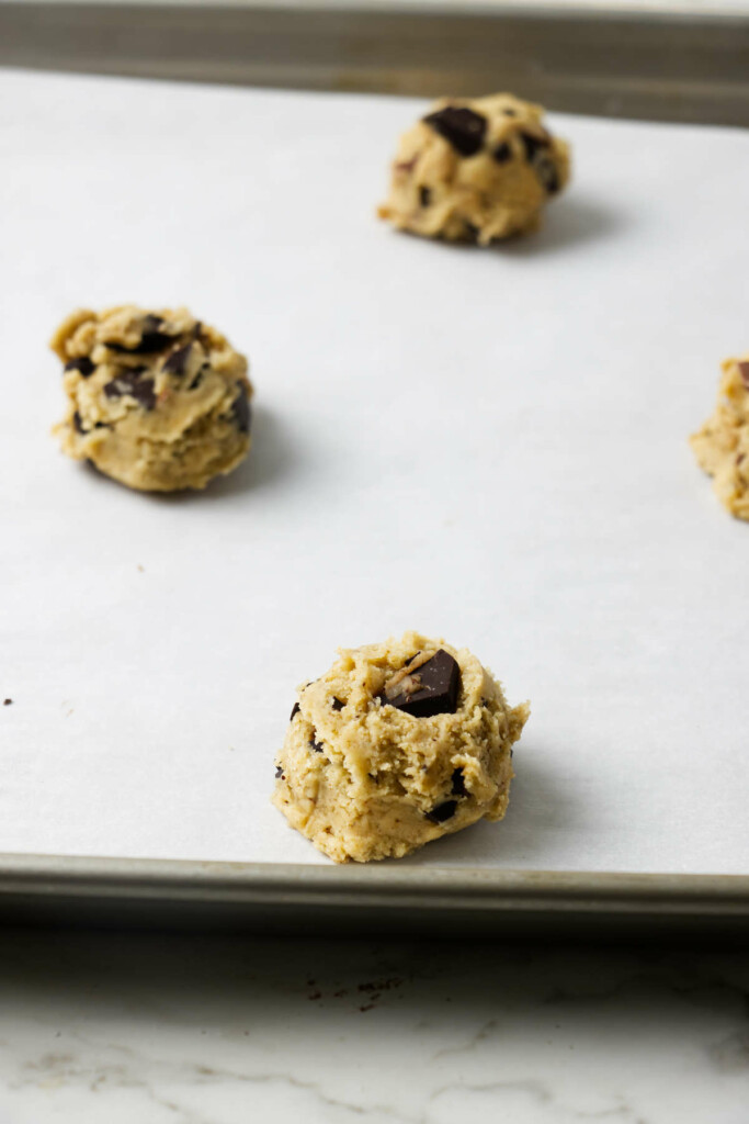 Balls of brown butter sourdough discard chocolate chip cookie dough on baking sheet.