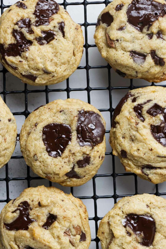 Freshly baked sourdough cookies with melted chunks on a cooling rack.