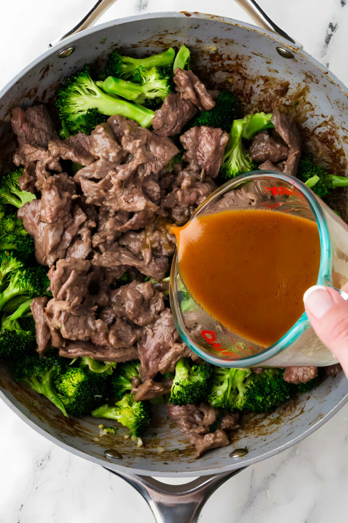 Adding Chinese stir fry sauce to a skillet with a broccoli beef stir fry.