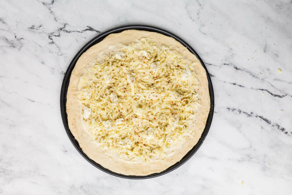 Bread flour pizza dough stretched on a pan and topped with cheese.