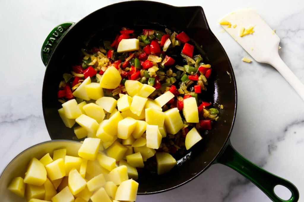 Adding cubed potatoes to the skillet. 