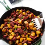 A spatula in a skillet filled with corned beef hash.