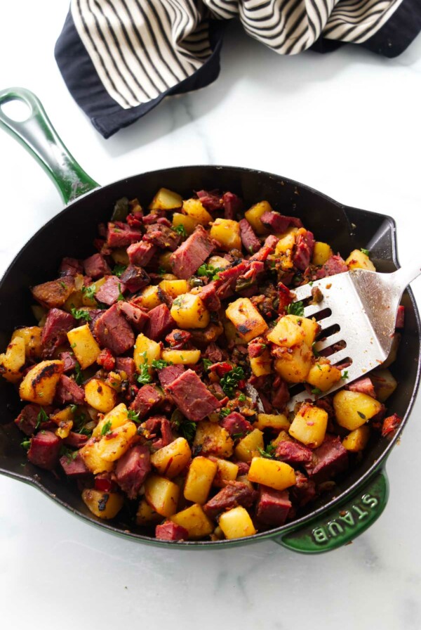 A spatula in a skillet filled with corned beef hash.