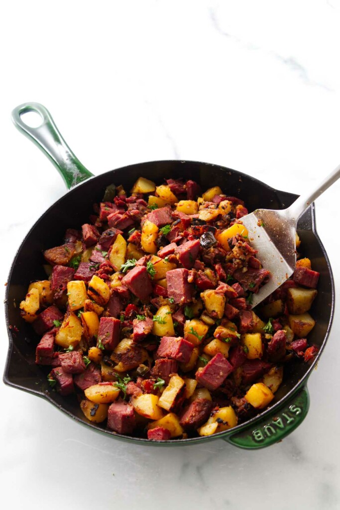 Potatoes and corned beef in a skillet topped with parsley. 