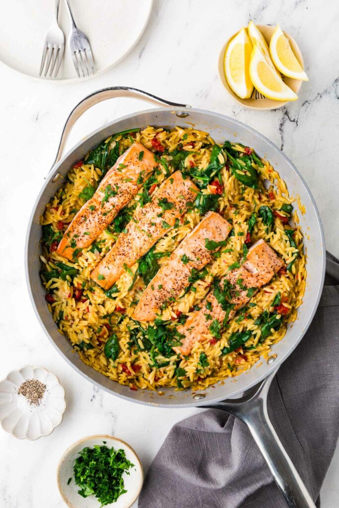 A one pan salmon orzo dinner in a skillet.