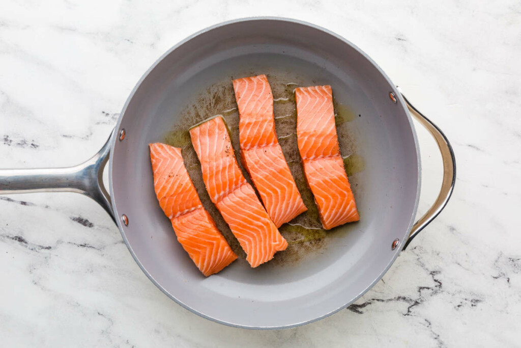 Cooking salmon fillets for one pan salmon and orzo dinner.