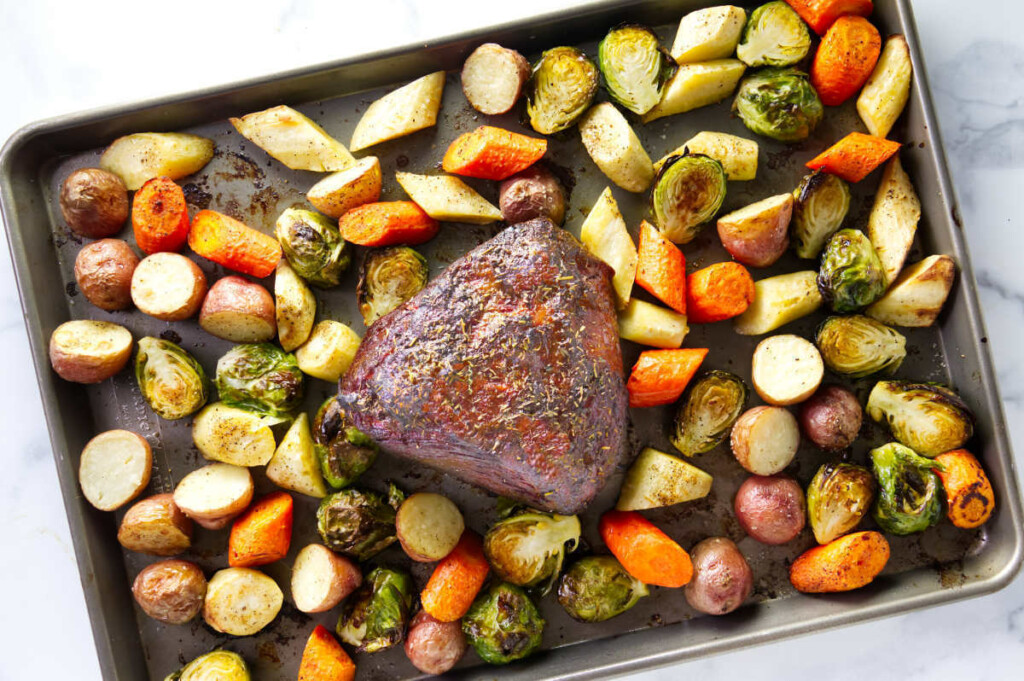 A sheet pan filled with corned beef, carrots, potatoes, brussels, and parsnips.