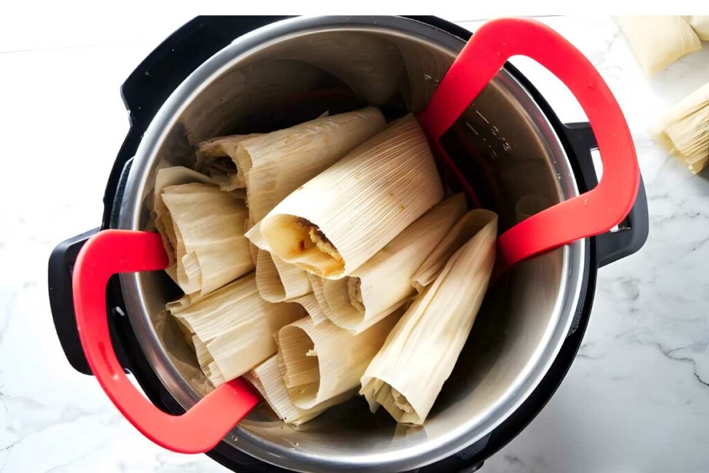 Tamales in corn husks upright in a pot, ready for steaming.