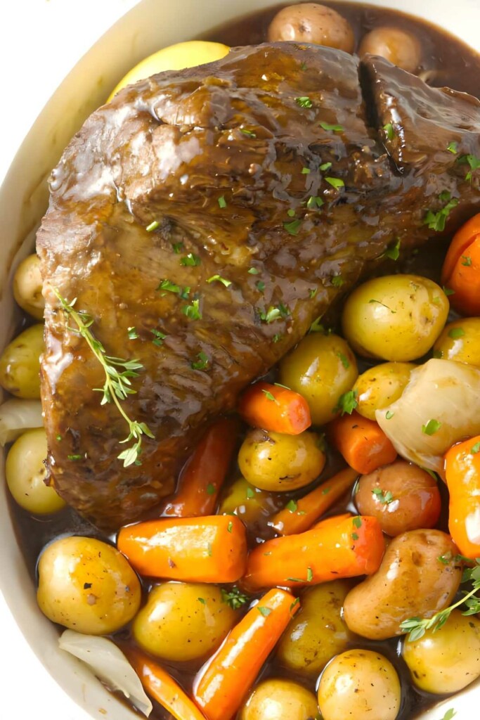 Pot roast with herbs, baby potatoes, carrots, onions, and brown gravy.