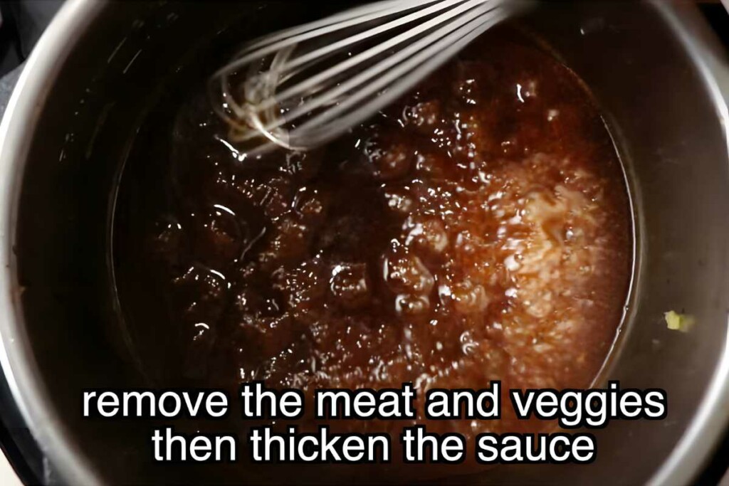Metal whisk stirring bubbling brown sauce in instant pot.