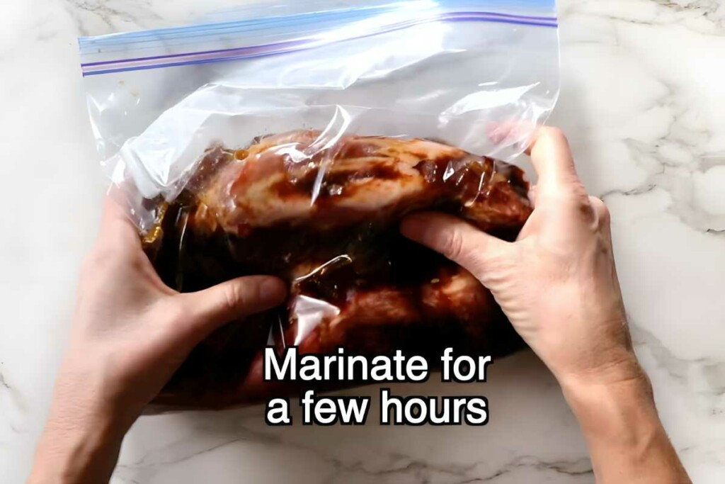 Sealing marinated raw tri tip in ziplock bag on marble countertop.