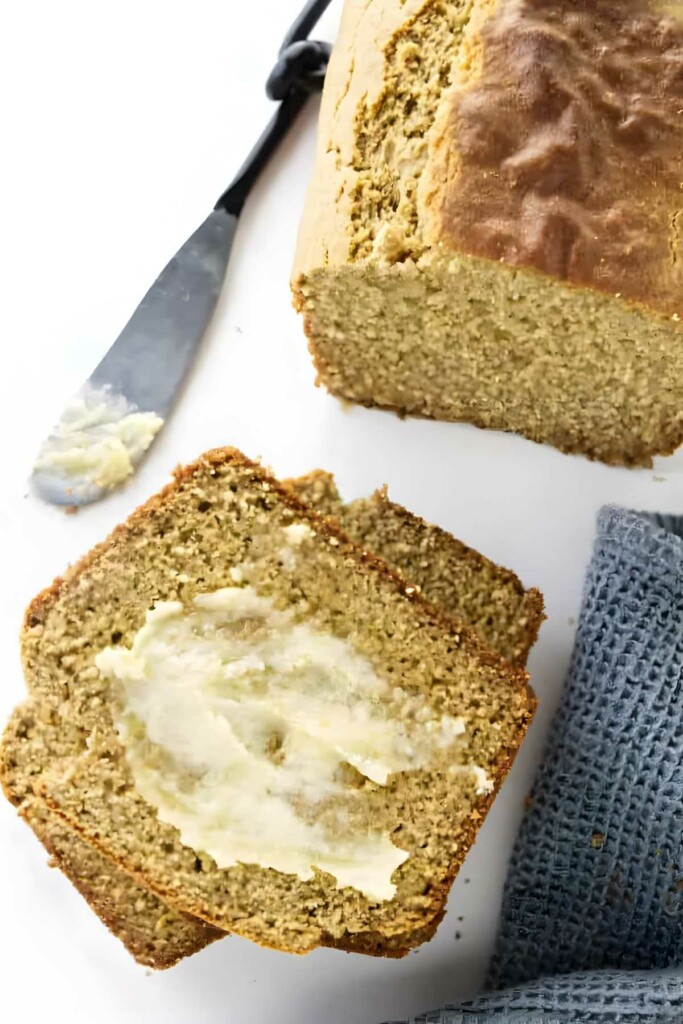 Sliced bread with buttered slice, butter knife, and blue cloth nearby.