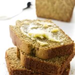 Three stacked bread slices with melting butter, loaf in background.