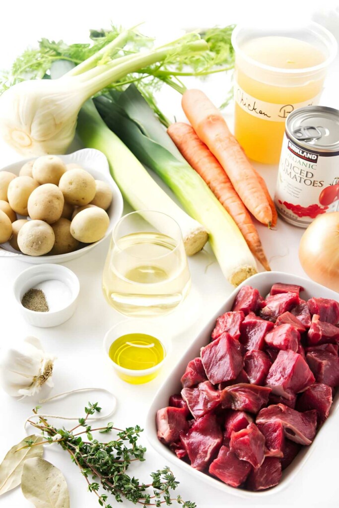 Assorted lamb soup ingredients arranged on white surface.