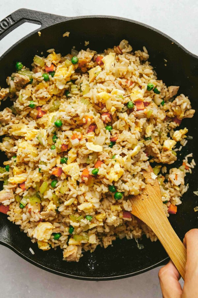 Stirring sauce into a wok with fried rice.