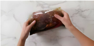 Adding a tri tip roast to a bag with marinade.