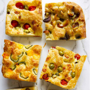 Sourdough focaccia topped with olives, tomatoes, cheese, and garlic.