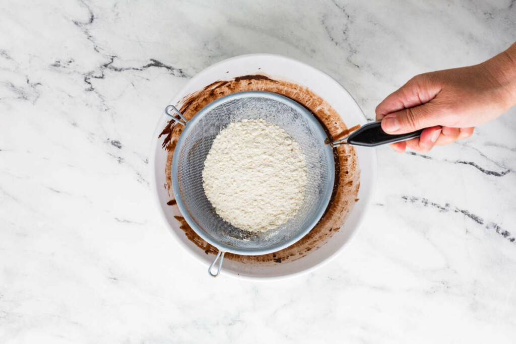 Sifting the dry ingredients over the cake batter.