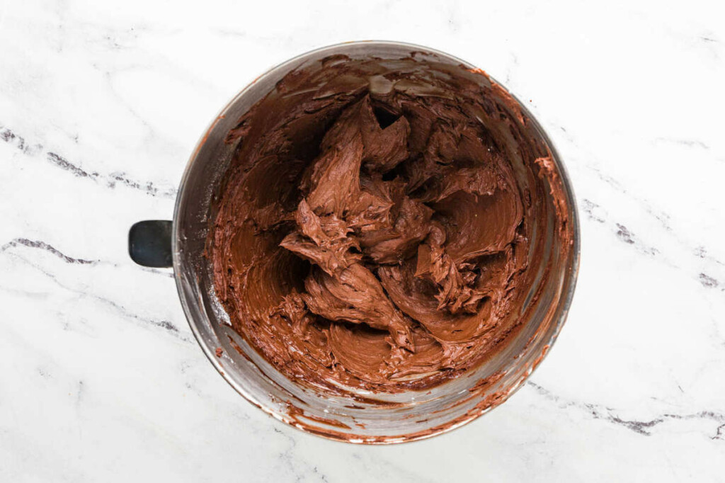 Beating the chocolate buttercream in the mixing bowl.