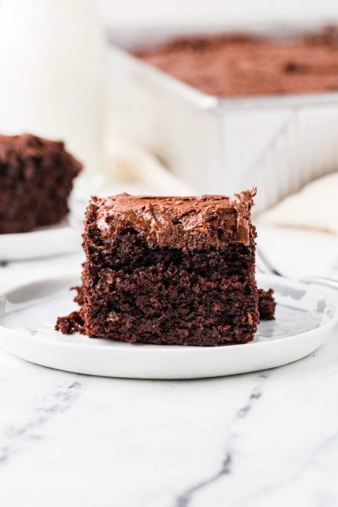 A slice of sourdough discard chocolate cake next to a cake pan.