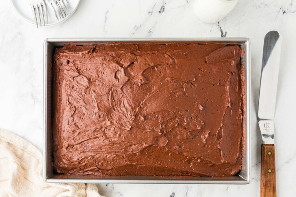 A 13 x 9 inch chocolate cake in a pan with chocolate buttercream.