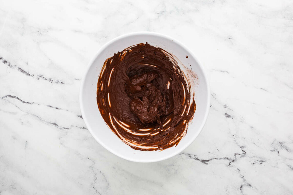 combining cocoa powder with hot water in a bowl.