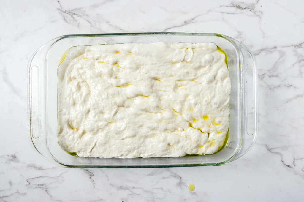 Spreading focaccia dough in a 13 x 9 inch pan.