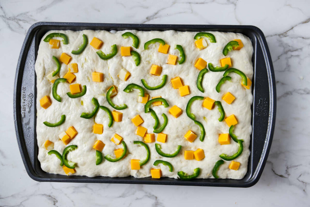 Topping focaccia bread with cheese and jalapeno pepper.
