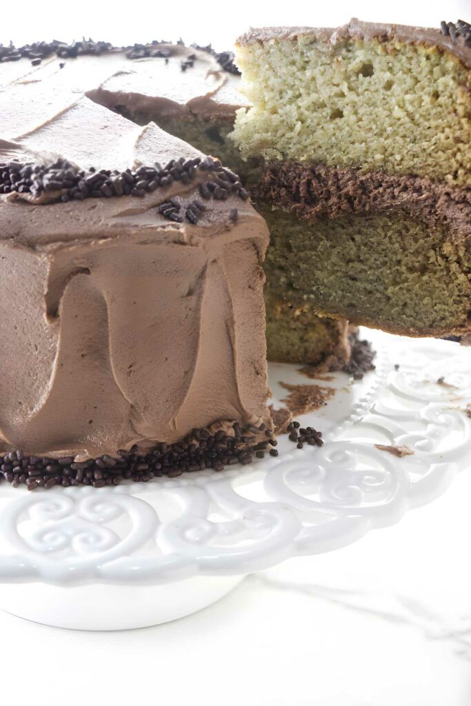 A two layer banana cake covered in nutella frosting on a cake plate.