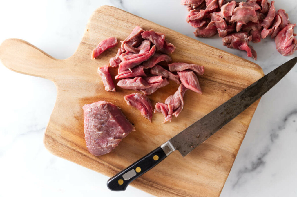 Slicing beef across the grain into thin strips.