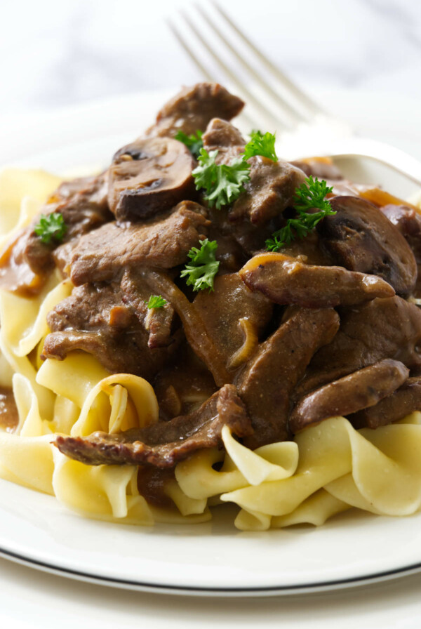Classic beef stroganoff with tender steak and creamy mushroom sauce, plated over egg noodles.