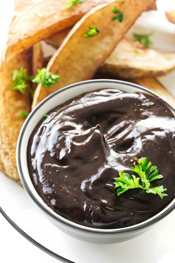 Bowl of black garlic aioli with parsley on top.
