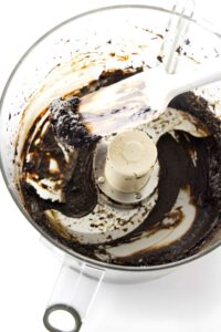 Black garlic being blended in a food processor.