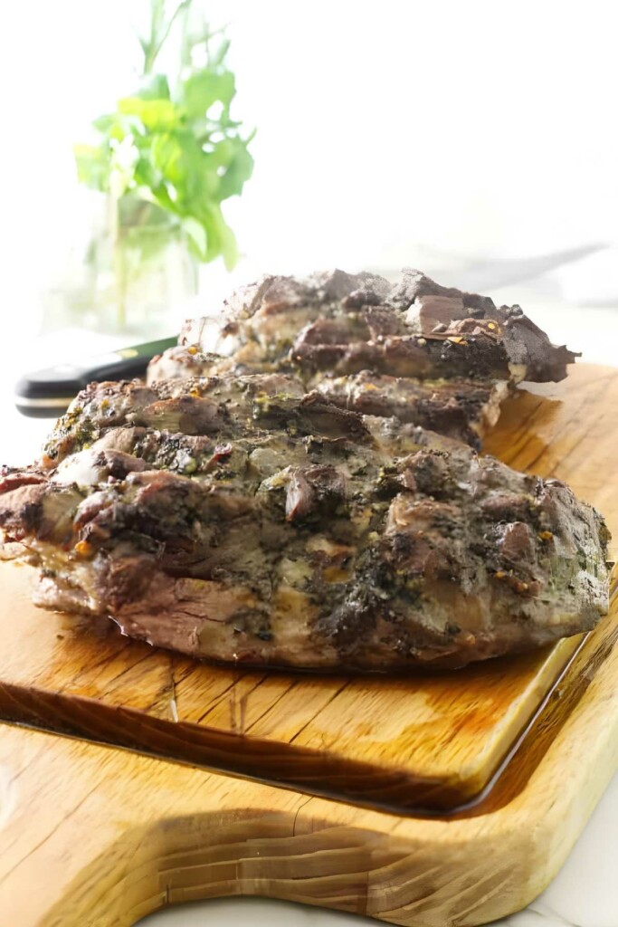 A butterflied leg of lamb on a wooden board.
