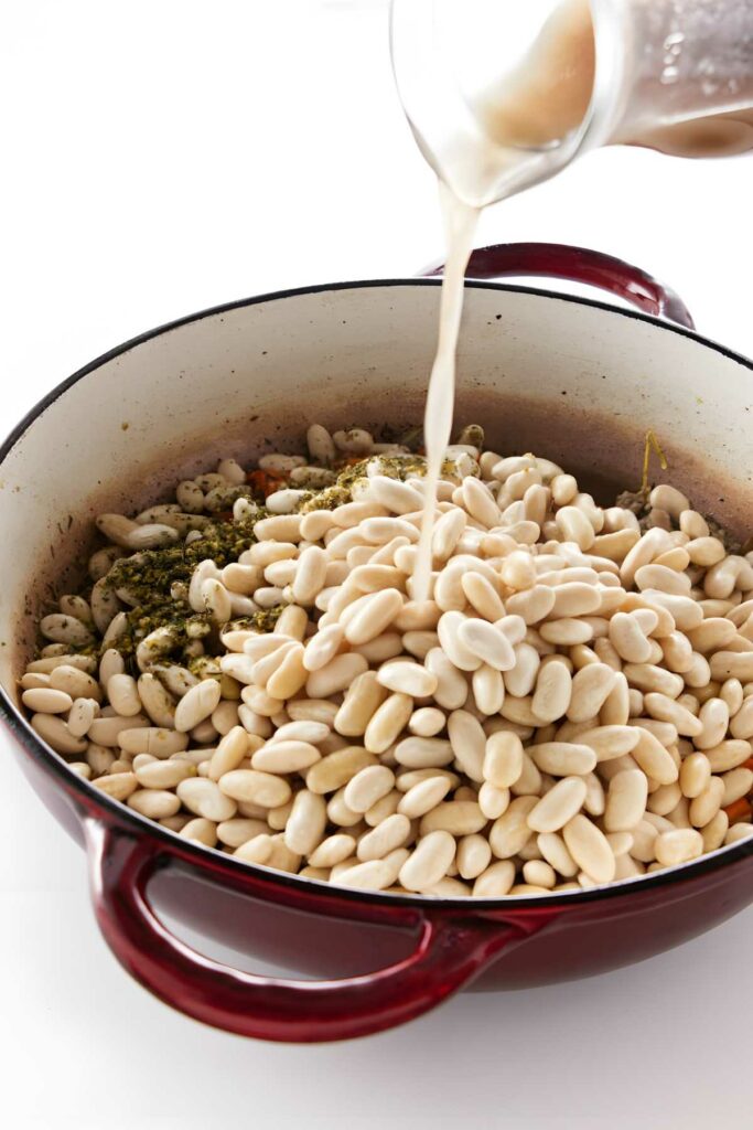 White beans in red pot with herbs.