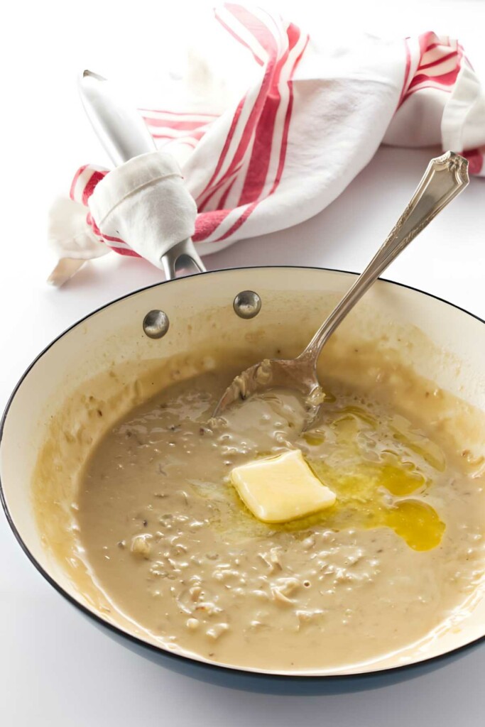 Pan of creamy pasta sauce with melting butter.