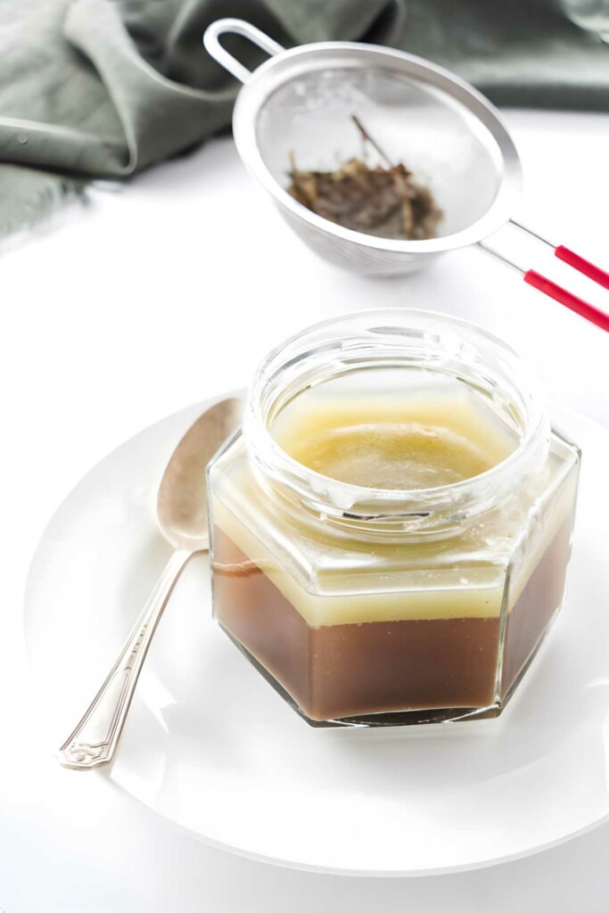Jar of duck fat next to herbs.