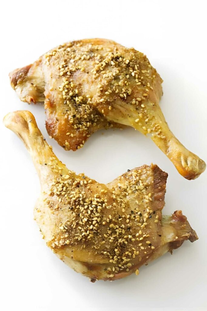 Two cooked duck leg quarters with Middle Eastern spices on a plain white background.